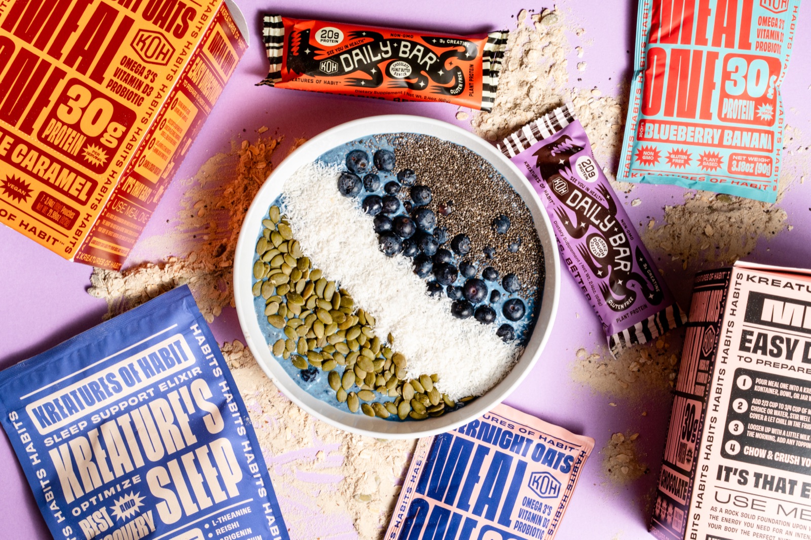 Kreatures of Habit spread — Meal One overnight oats bowl with blueberries surrounded by Daily Bars and product packaging